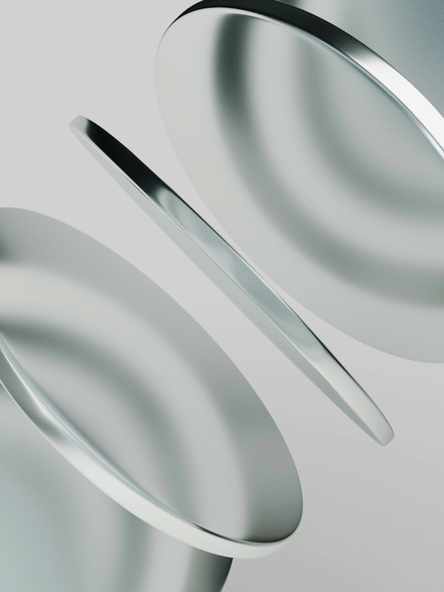 Three smooth metallic discs floating at an angle against a light grey background